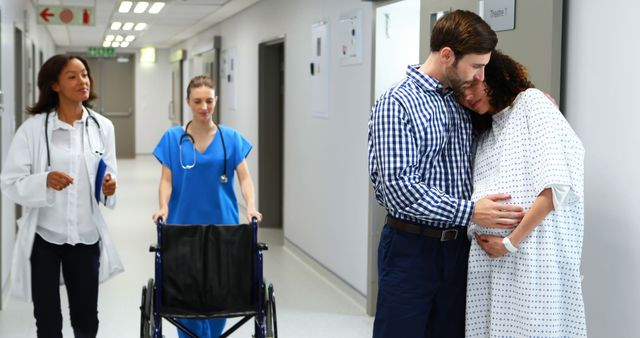 Pregnant Woman and Partner Embracing in Hospital Corridor, Medical Staff Assisting - Download Free Stock Images Pikwizard.com