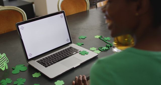 Happy african american woman making image call using laptop with copy space. st. patrick's day, irish tradition, domestic life, spending time at home.