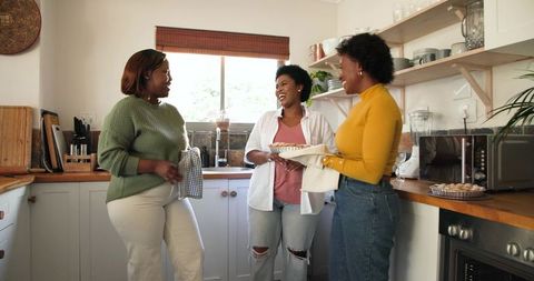 Friends laughing in kitchen while baking pastries together