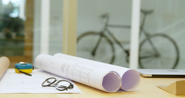 Architectural plans on desk with bicycle in background - Download Free Stock Images Pikwizard.com