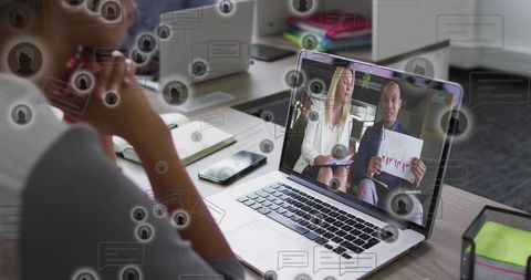 Team watching virtual meeting on laptop with presenters holding chart and chat overlays