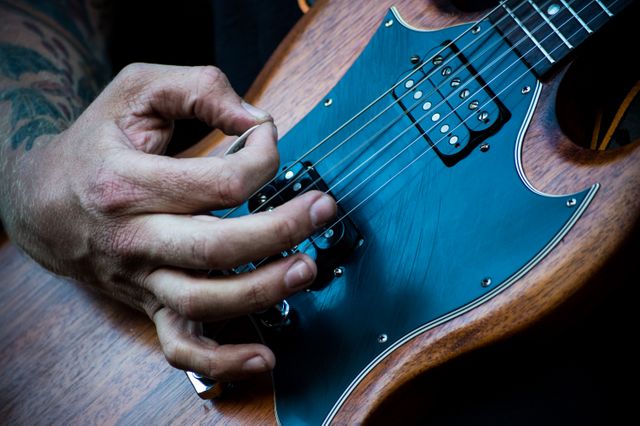 Image shows a close-up of a guitarist’s hand playing an electric guitar. Ideal for use in advertisements or promotions related to music lessons, rock concerts, musical instruments, or band merchandise. It captures the essence of live performance and musical focus.