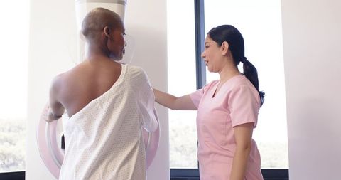 Mammography screening: technician positioning female patient for breast exam in clinic