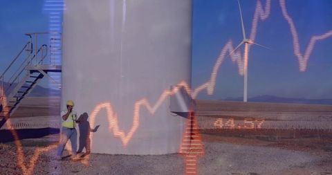 Wind farm technician analyzing data at turbine base