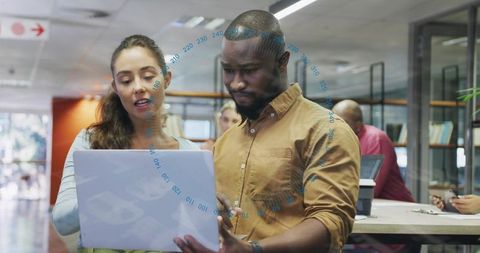 Diverse colleagues collaborating over laptop in modern open-plan coworking office