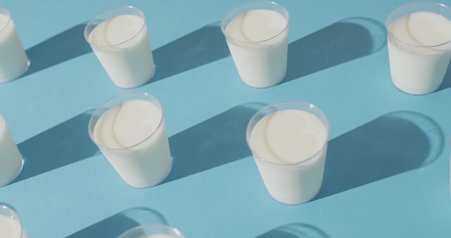 Image of row of glasses of milk on blue background. dairy products and healthy organic nutrition.