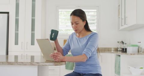 Woman Enjoying Coffee and Tablet in Modern Kitchen