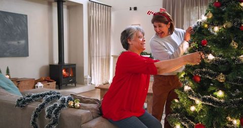 Senior mother and daughter decorating christmas tree at home