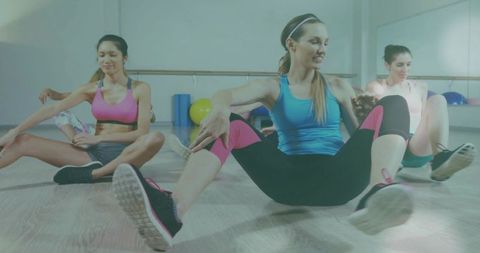 Women stretching in group fitness class using barre and stability balls