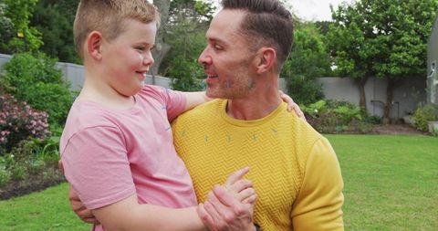 Father holding son in backyard embracing joyful family moment for parenting and lifestyle