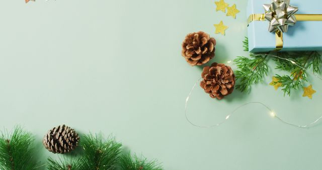 Christmas gift-wrapping idea with pinecones and string lights on a green background creates a festive mood. Perfect for holiday-themed promotions, Christmas greeting cards, blog posts about gift ideas, or advertisements for festive decor products.