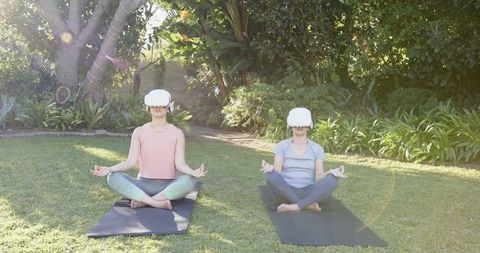 Two Women Meditating with VR Headsets in a Tranquil Garden