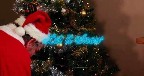Santa claus decorating christmas tree with neon sign