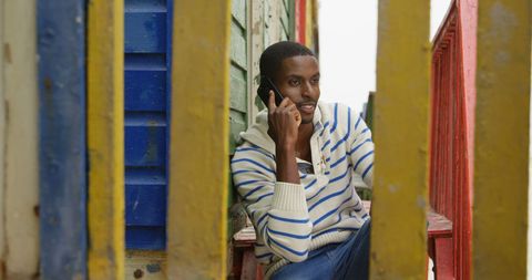 Young Man on Mobile Phone Between Colorful Wooden Panels - Download Free Stock Images Pikwizard.com
