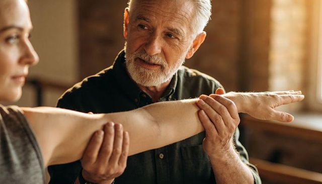 Senior physical therapist guiding arm extension during rehabilitation assessment