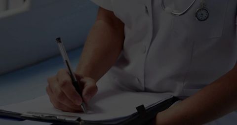 Mid-adult clinician writing patient chart with stethoscope and clipboard closeup
