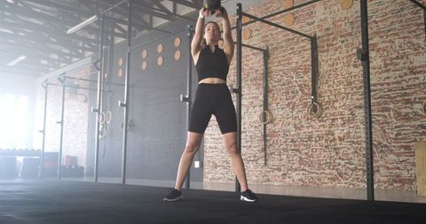 Woman Performing Kettlebell Swing in Industrial Style Gym