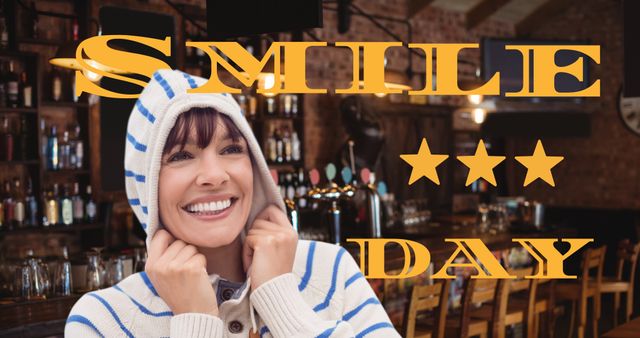 This image shows a cheerful woman in a cozy striped sweater, smiling happily in a bar setting. The large text 'Smile Day' is prominently displayed, making this perfect for promoting happiness and positivity. Ideal for use in social media campaigns, wellness sites, and advertising happiness-related events or products.