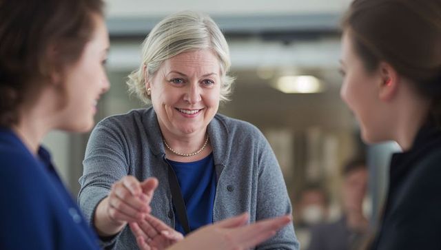 Senior woman greeting younger colleagues with warm handshake in modern office lobby