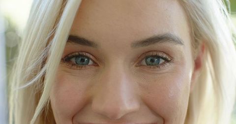 Close-up blonde woman gazing smiling with natural makeup and visible skin texture