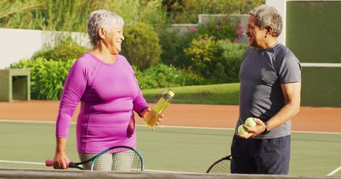 Senior Couple Enjoying Tennis Game on Sunny Afternoon