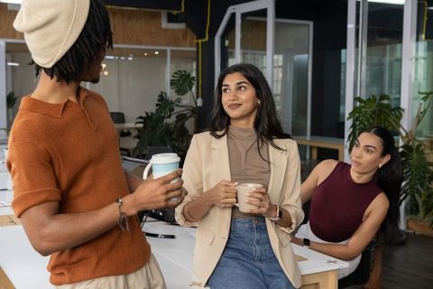 Diverse team chatting over coffee in modern open-plan office for collaboration