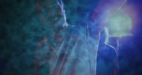 Charismatic Singer Performing on Stage Amidst Vivid Smoke Effects