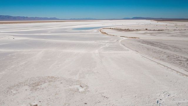 Stretching salt flats with shallow water channels and tire tracks on desert expanse