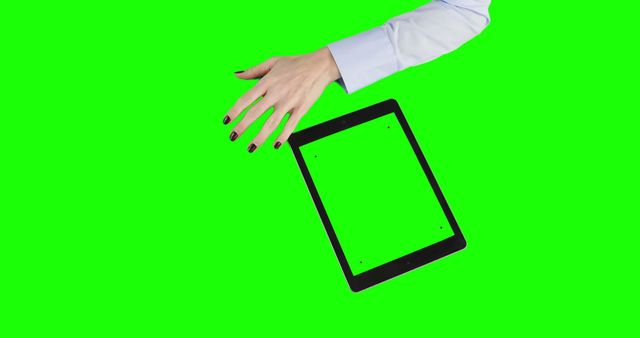 A Caucasian hand reaches towards a tablet with a blank screen on a green background, with copy space. Ideal for presenting digital technology or advertising with a customizable screen.