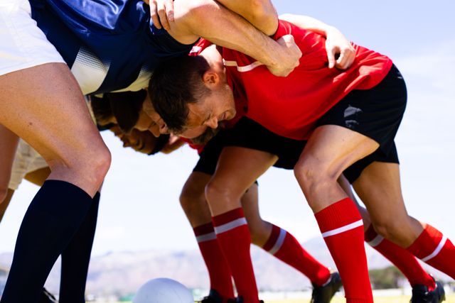 Rugby players from two teams engage in a powerful scrum on the field, showcasing teamwork and physical strength. Ideal for use in sports articles, athletic event promotions, and teamwork-related content.