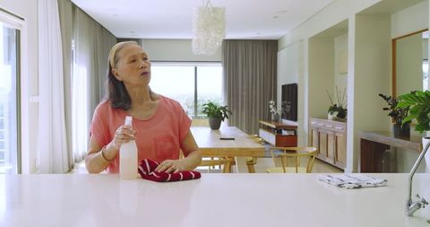 Senior Woman Cleaning Kitchen Countertop with Spray Bottle