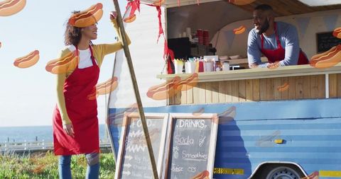 Seaside food truck staff serving customers with chalkboard menus and colorful bunting