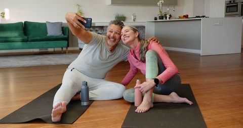 Senior Couple Smiling on Yoga Mats Taking Selfie at Home
