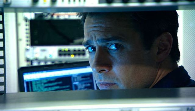 Monitoring it technician checking server rack and code on laptop screen in datacenter
