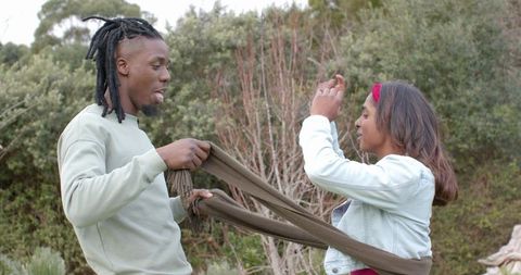 Multicultural couple wrapping olive knit scarf and sharing cozy moment during autumn walk
