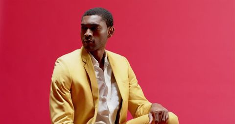 Confident Man In Yellow Suit Against Bold Pink Background