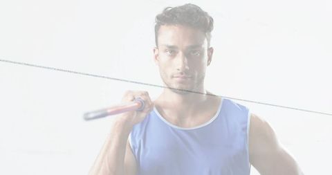 Athlete holding pole on shoulder wearing blue tank top in high-key studio portrait