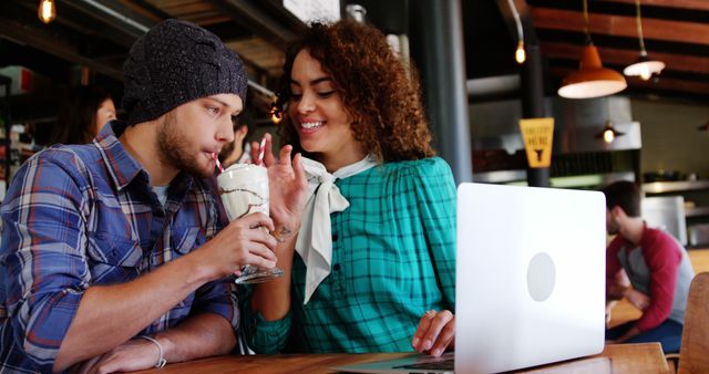 Young Couple Sharing a Milkshake at Cozy Café with Laptop - Download Free Stock Images Pikwizard.com