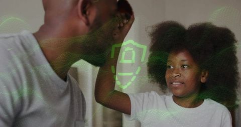 High-fiving dad and daughter celebrating home cybersecurity with green hologram shield