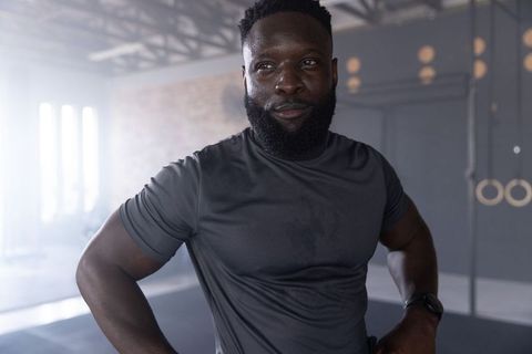 Confident african american athlete posing hands on hips in industrial crossfit gym