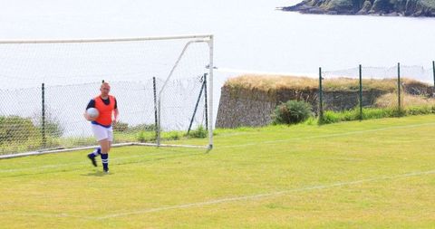 Goalkeeper holding ball on coastal soccer pitch