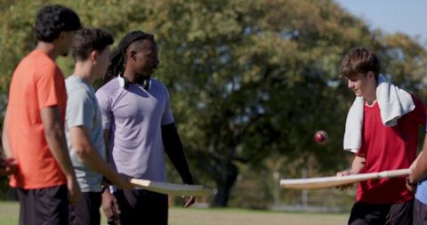 Coaching teen batter in park tossing ball for bat control teamwork and outdoor youth sports