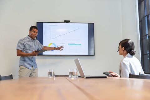 Diverse Team Analyzing Data on Wall Monitor During Business Meeting