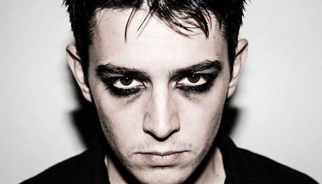 Intense man staring with smudged eyeliner and dark eye makeup moody high-contrast portrait