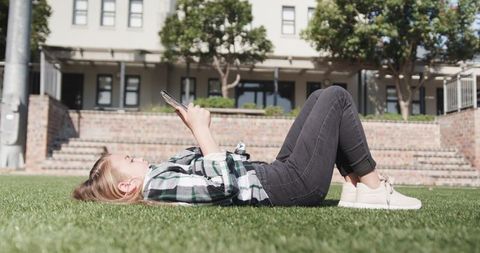 Girl Relaxing on Lawn Looking at Smartphone in Sunny Park