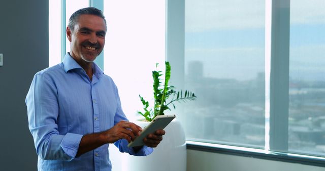 Smiling Mature Businessman Using Tablet Near Large Window - Download Free Stock Images Pikwizard.com