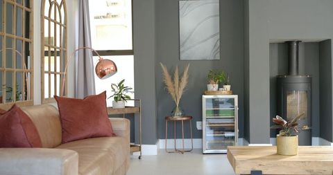 Contemporary living room with tan leather sofa, rust pillows, copper lamp and wood stove
