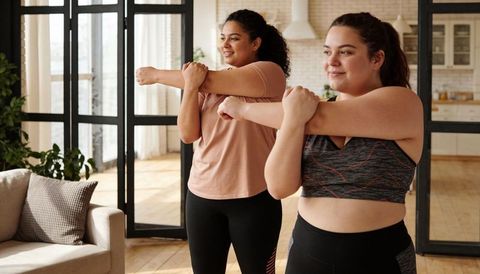 Plus-size women stretching together in sunlit loft workout embracing body-positive fitness