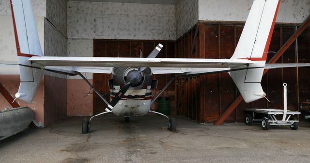 Small propeller airplane with dual tail stored in aviation hangar. Suitable for aviation training materials, aeronautical engineering guides, airport operation visuals, and travel industry promotion.