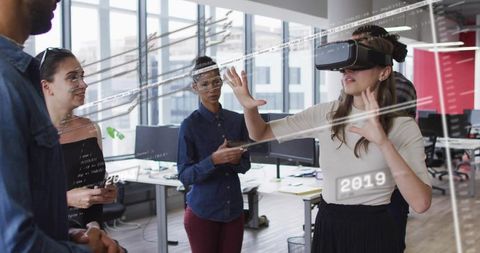 Team collaborating, woman wearing VR headset using mixed reality overlays in office